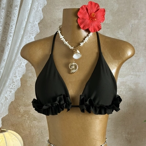 Detail of black halter bikini top with tiered ruffles on a summer beach background