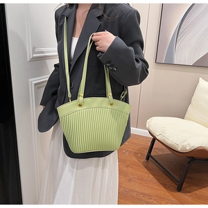 Detail of light green pleated shoulder bag with gold metal rings on a grey suit outfit