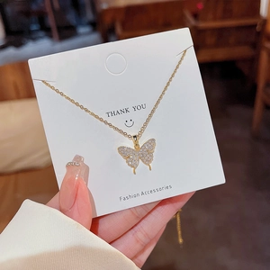 Gros plan sur le collier papillon doré avec zircons sur carte de présentation