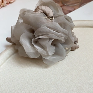 Détails d'une pince à cheveux fleurie en organza mauve avec une perle de style vintage
