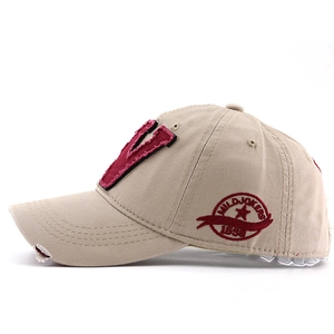 Détail de la casquette kaki en coton avec logo brodé rouge et bord de visière usé