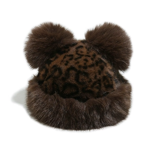 Close-up of fluffy leopard print plush winter hat featuring large brown faux fur pom-poms