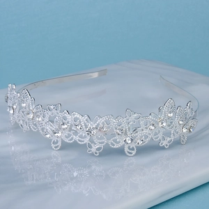 Detail shot of silver rhinestone crown headband with intricate hollow patterns on a stand