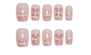 Détail de faux ongles œil de chat roses avec nœuds rouges et pois colorés