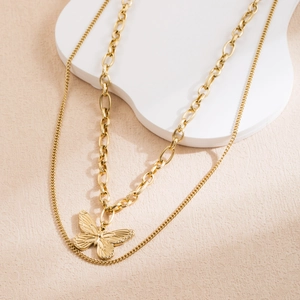 Détail d'un collier double épaisseur doré avec un pendentif papillon raffiné et élégant