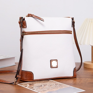 Detail of white lychee textured crossbody bag with brown leather trim and gold hardware