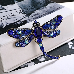 Macro detail of dragonfly brooch with blue crystals and vintage gold metallic finish