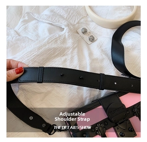 Detail of adjustable black wide strap and metal buckle on pink studded box bag