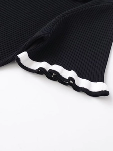 Close-up of contrast white wavy trim on black knitted polo shirt sleeve and hem