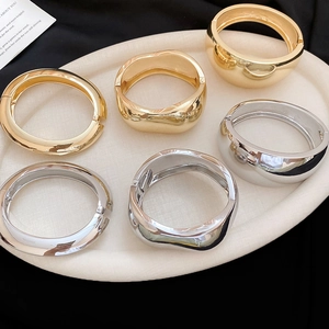 Detailed set of polished gold and silver oval bangles in smooth and wavy metal textures