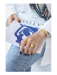 Model wearing gold heart shell ring and chain design ring with irregular open bangle