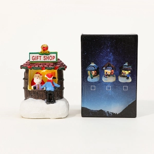 Détail d'une maison de Noël lumineuse en résine avec son coffret cadeau festif