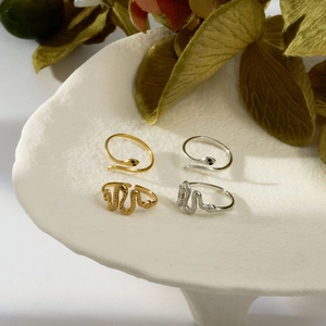 Close-up of gold and silver snake rings with scale textures and black eye accents