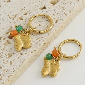 Détail de boucles d'oreilles abeille dorées avec perles vertes et orange sur pierre