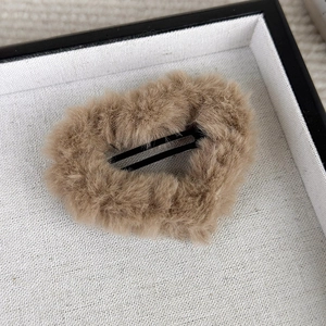 Detail of a plush light brown heart-shaped hair clip with soft faux fur texture