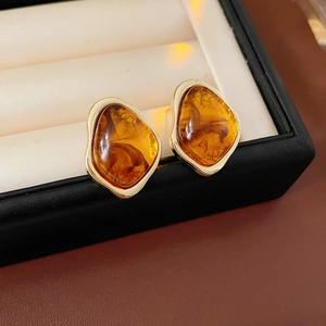Macro shot of amber geometric earrings with gold border on white velvet jewelry box
