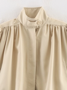Close-up of stand-up collar and pleated shoulder detail on apricot French blouse