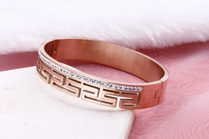 Detail of rose gold bangle with hollow Greek key pattern and sparkling crystal inlay