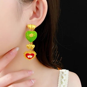 Detailed close-up of vintage heart drop earrings with enamel and pearls on a model