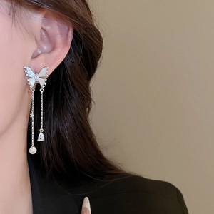 Close-up of butterfly earrings with pearl tassels and shimmering zircon on a model