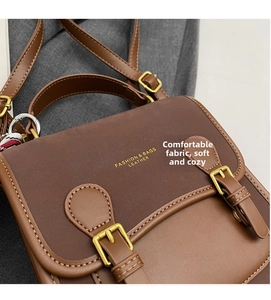 Detail of vintage brown leather bag with dual decorative buckles and fine stitching