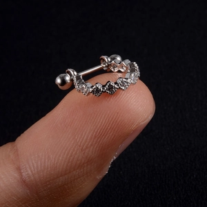 Macro shot of silver zircon ear cartilage ring with wavy design and ball screw closure