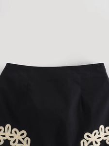 Gros plan détaillé du tissu de jupe noir avec des fleurs au crochet blanches sur l'ourlet