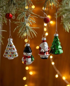 Detail view of four festive glass Christmas ornaments hanging on a pine tree branch