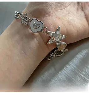 Close-up of silver star and heart charms on a sleek metal chain bracelet worn on a wrist