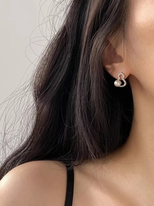 Detailed close-up of a pearly gourd stud earring with sparkling cubic zirconia on model