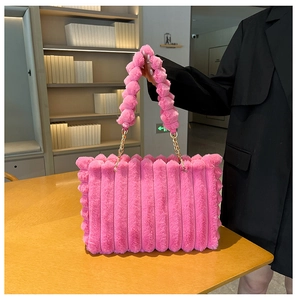 Detail of pink plush tote bag with vertical rib texture and golden chain handle detail