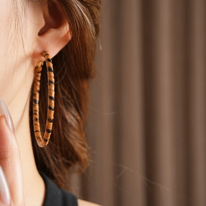 Gros plan d'une boucle d'oreille créole en cuir léopard portée par un mannequin