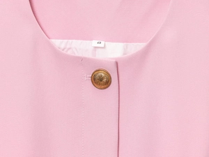 Dettaglio dello scollo del gilet rosa con bottone dorato a rilievo ed etichetta taglia S