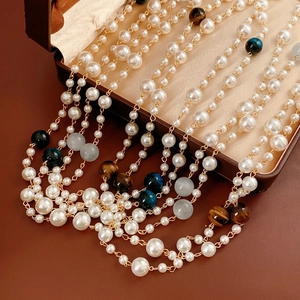 Vintage multi-layer pearl necklace with tiger eye stones on brown leather display