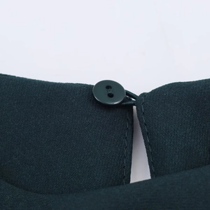 Dettaglio dell'abito midi verde scuro con bottone sulla nuca e trama in twill raffinato