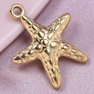 Detailed close-up of golden starfish pendant on pink silk with textured surface
