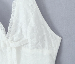 Close-up of white lace V-neck dress featuring delicate floral embroidery and soft textures