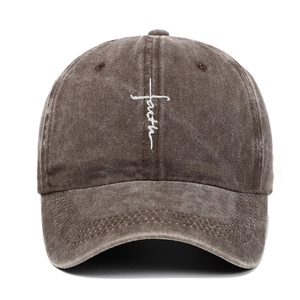 Detailed close-up of white faith embroidery and cross on brown washed cotton baseball cap