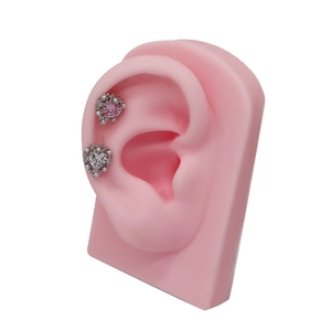Dettaglio di orecchini a cuore con zircone rosa e perle su un modello di orecchio