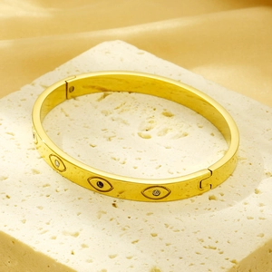 Detailed view of a gold Evil Eye bangle with embedded crystals on a luxury stone base