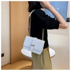 Close-up of white crocodile pattern shoulder bag with a stylish gold chain and metal buckle