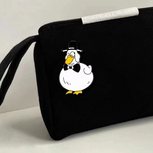 Cute white enamel duck brooch with black hat pinned on a black canvas fabric bag