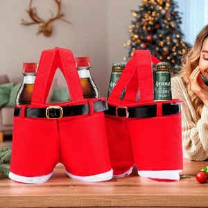 Detail of two red Christmas suspender pant bottle bags on a festive wooden table