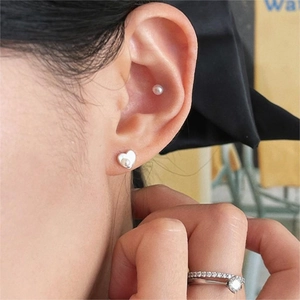 Close-up of 925 sterling silver heart pearl earrings and rings set on female model