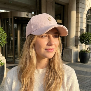 Pink herringbone wool baseball cap with gold letter C logo worn by a model outdoors