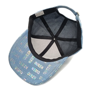Detail view of light blue denim baseball cap featuring colorful QUEEN letter embroidery