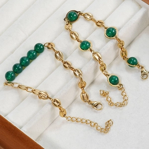 Macro shot of gold-plated stainless steel chain with natural emerald green stone beads