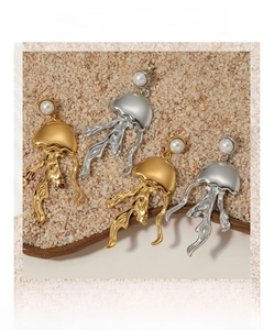 Macro detail of gold and silver jellyfish earrings with pearls on sand background