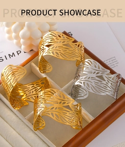 Detail of leaf pattern hollow bangles in gold and silver finish on grey velvet tray