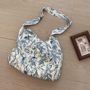 Flat lay view of a vintage blue floral canvas tote bag on a light wood background